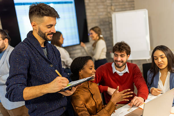 istock Four business professionals looking at tablet with colleagues in background 2254744785