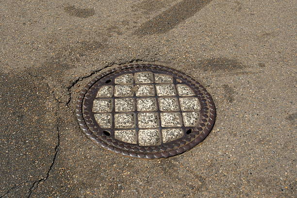 Old concrete and iron manhole cover in the middle of a road.