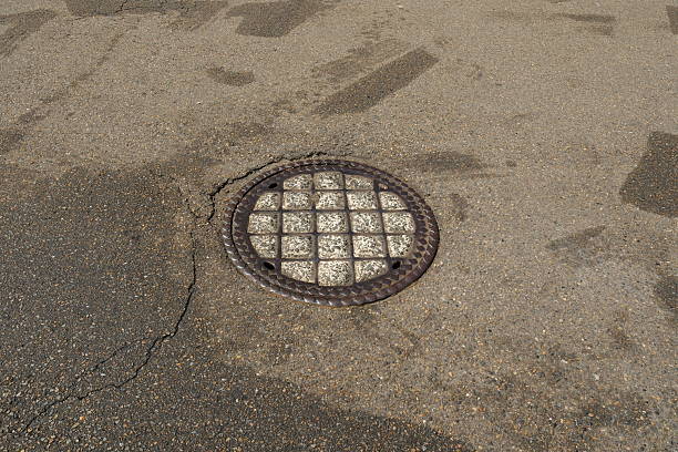 Cenaia, Italy - October 24, 2019: a closed manhole has the same colour as the pavement and is further patterned by the first drops of falling rain