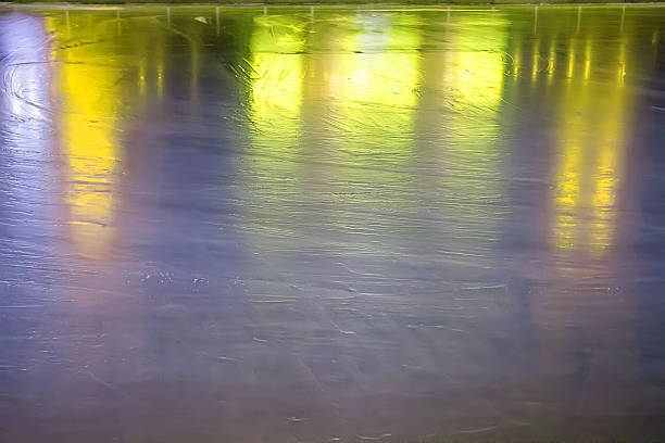 Ice rink surface reflects colorful lights at night creating abstract winter background with calm festive seasonal mood