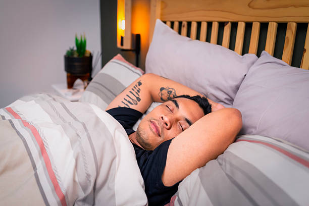 istock Man Sleeping Peacefully in Cozy Bedroom With Tattoos Resting On Bed 2254750482
