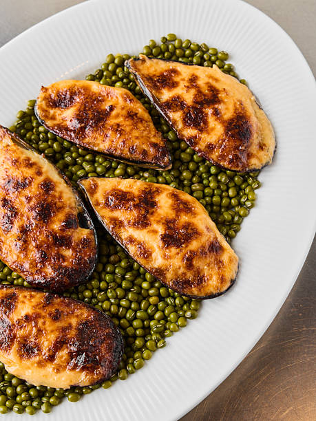 Elegant serving of roasted mussels on peas with lemon wedge