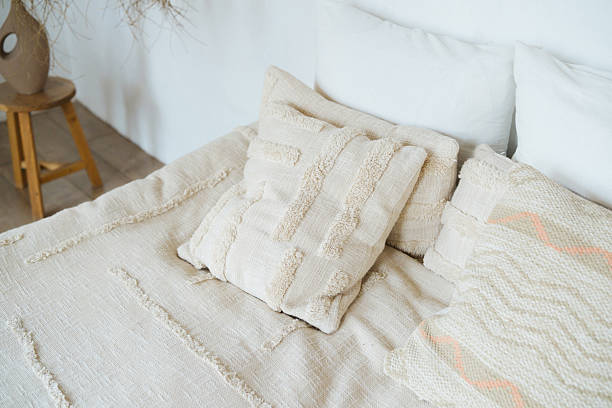 istock Cozy bed with textured pillows and a woven blanket, warm and inviting home interior decor. 2254751371