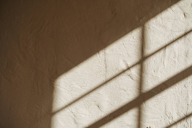 istock Sunlight stripes cast across a textured wall creating a graphic pattern of light and shadow. 2254751392