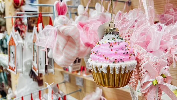 Charming cupcake ornament with pink frosting and colorful sprinkles hanging in a festive store display