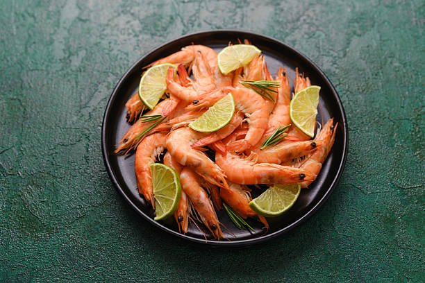istock Shrimp and lime in black bowl on green rustic surface for seafood freshness or summer menu concept 2254751819