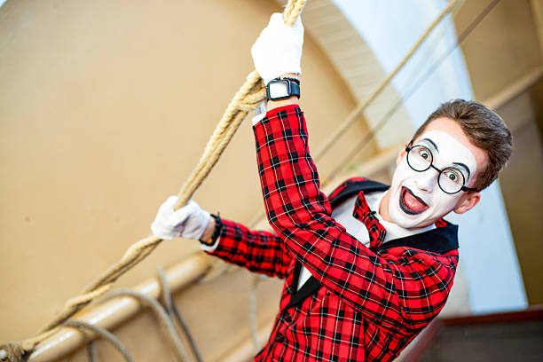 A mime wearing glasses pulls a rope. The actor shows off the emotions, with space for text nearby