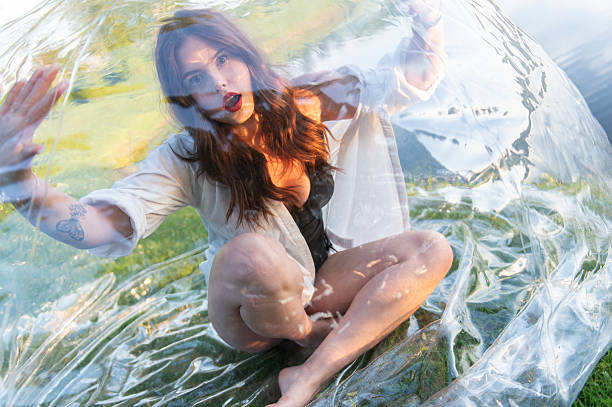 Water ball (similar to zorb or Human Hamster Ball) with young woman inside on pond surface