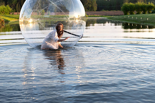 istock Water ball (similar to zorb or Human Hamster Ball) with young woman inside on pond surface 2254756681