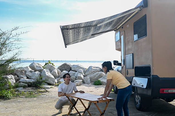 Preparing breakfast from a campervan, the couple enjoys a scenic seaside setting, highlighting spontaneity and exploration.