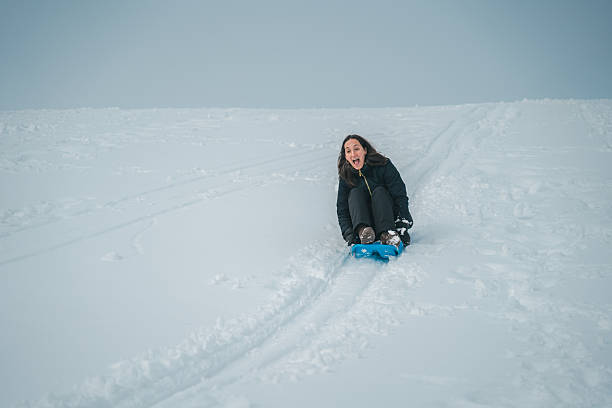 istock A woman is sitting on a blue sled in the snow 2254761114