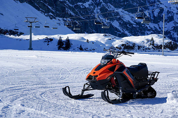 Sella di Razzo, Italy: a small group of people riding four snowmobiles on the Dolomites in Cadore, Veneto region