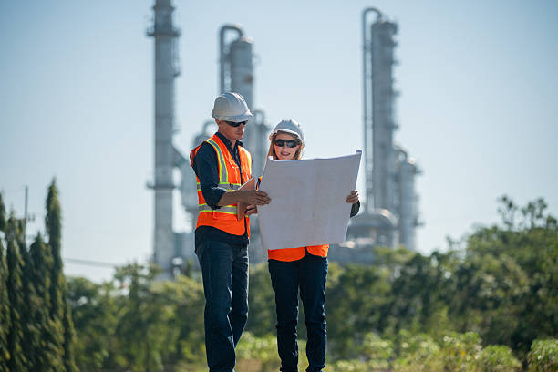 istock Industrial engineer wearing safety helmets and vests inspection technical plan and data on tablet with tall refinery towers rise background is industrial safety and carbon credit environment operations concept. 2254762495