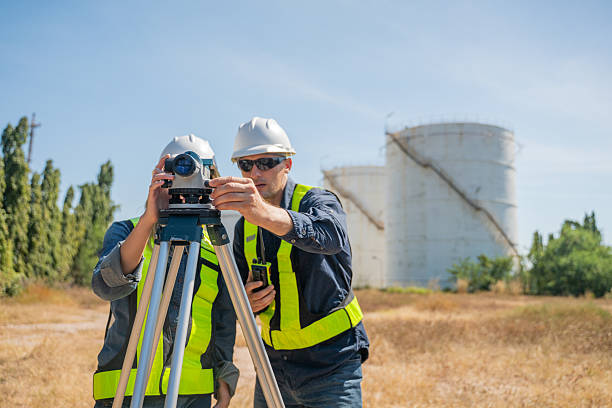 istock Engineer or worker site inspection or surveying activity industrial  tripod suggesting the work may involve geodetic or structural measurement tasks with oil refinery background. 2254764112