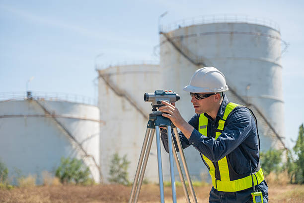 istock Engineer or worker site inspection or surveying activity industrial  tripod suggesting the work may involve geodetic or structural measurement tasks with oil refinery background. 2254764200