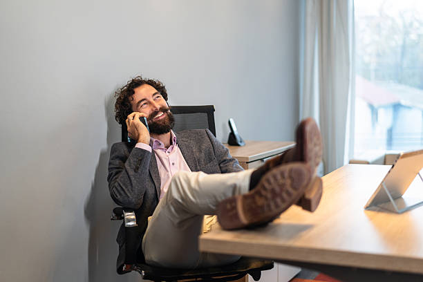 istock Happy man relaxing at office during phone call 2254767641