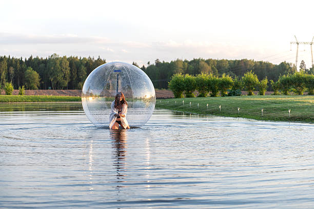 istock Water ball (similar to zorb or Human Hamster Ball) with young woman inside on pond surface 2254769001