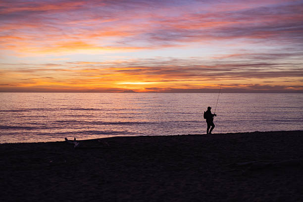 Silhouette of a young man fishing at morning sunrise in Antalya Turkey