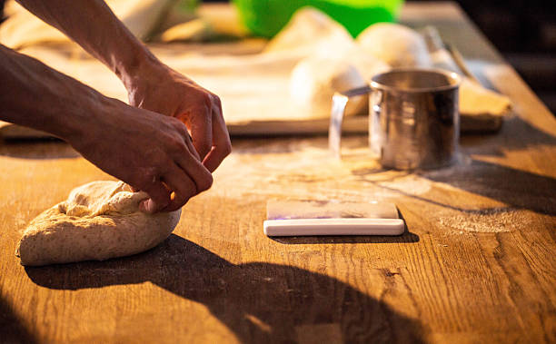 Hands kneading dough on wooden table in warm light, preparing to bake bread or pastry, showcasing process of handmade food creation
