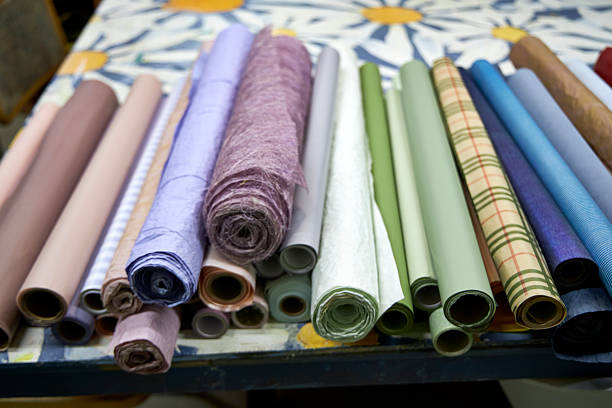 Colorful rolls of wrapping and craft paper neatly arranged on a creative workshop table. Artistic workspace with decorative materials, texture variety, and post-holiday gift wrapping supplies
