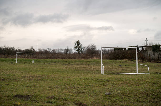 A soccer field sits empty under a cloudy sky. The goals stand ready, awaiting players for a game or practice, but for now, it's a quiet scene.