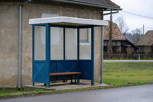 Empty illuminated advertising billboard inside a bus stop shelter at night with glass panels, seating, and reflections, prepared for outdoor marketing or branding display.