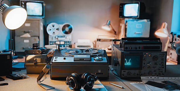 Retro microphones, red TV, radio, top hat with goggles, index finger and old pocket watches on table front mint blue wall background. Vintage style filtered conceptual photo