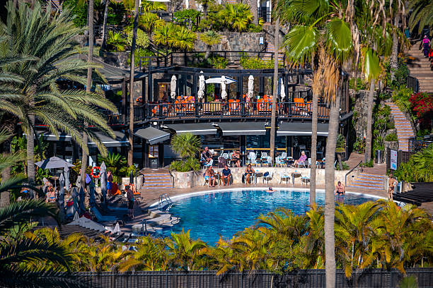 People enjoying beautiful pool surrounded by palm trees at luxury resort in Maspalomas,  Gran Canaria - Corallium Dunamar by Lopesan Hotels