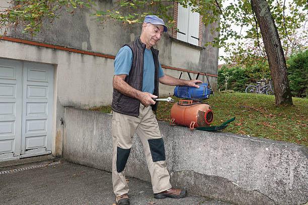 A person is repairing engine with tools near a wall in a garden
