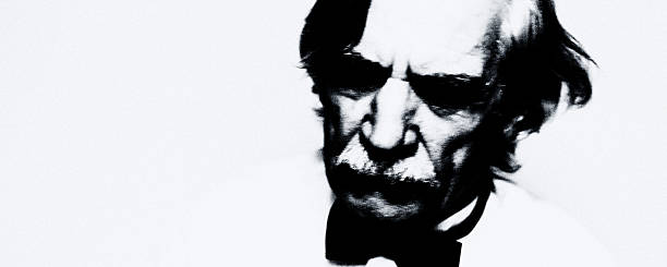 An extremely high-contrast black-and-white portrait showing an elderly man’s face between visibility and dissolution.