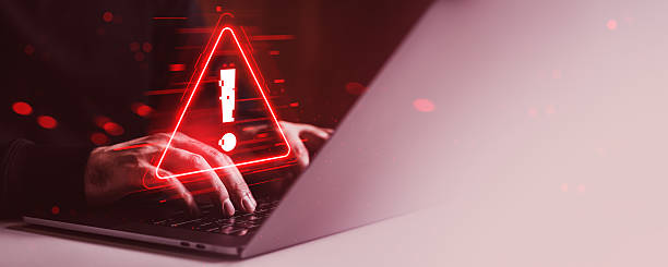 istock Cybersecurity warning alert on laptop screen with hands typing in dark red environment, digital glitch effects and creative concept background. 2254779359