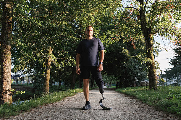 Man with a disability, using a versatile prosthetic leg, walking along the greenway during daily recreation and relaxation activities.