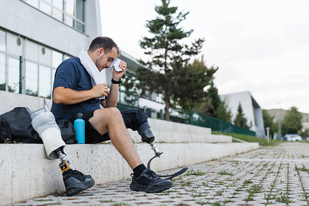 istock Athlete with leg amputation resting on outdoor steps, wiping sweat after workout 2254781465