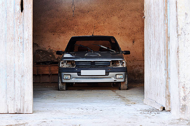 istock Old Damaged Car Resting In A Weathered Garage With Front View And Dusty Floor 2254786568