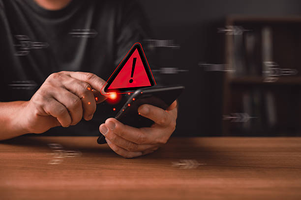 istock person uses a smartphone with a glowing red warning triangle icon symbolizing caution,notification alert,danger,cybersecurity risks,system errors,malware threats,and important digital safety messages. 2254786688