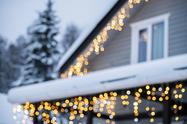 Snowy blurred winter house in forest with bokeh of festive Christmas lights on creating dreamy holiday atmosphere and warm seasonal background. Celebration themes.