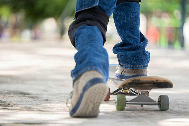 A POV of a skater in baggy jeans and cool graphic T-shirt skateboarding on a concrete floor