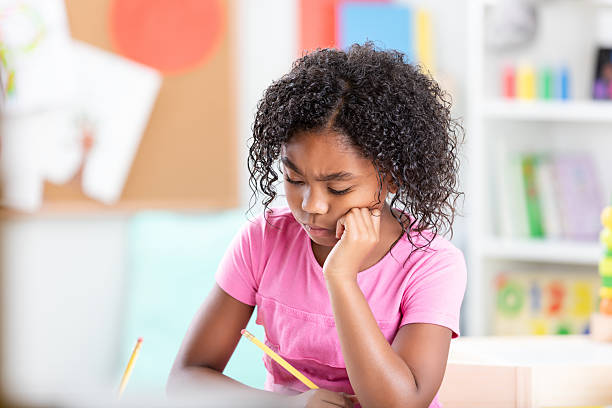 istock Young student looks upset while focusing on schoolwork, struggling with homework at a desk. 2254793037