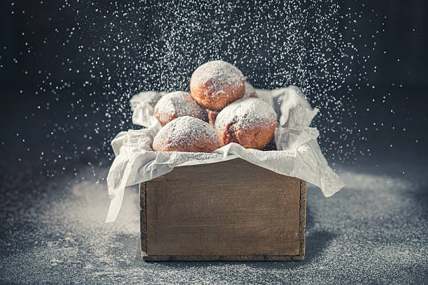 Fresh and sweet mini doughnuts deep frying in oil. Doughnuts with sugar for Fat Thursday.