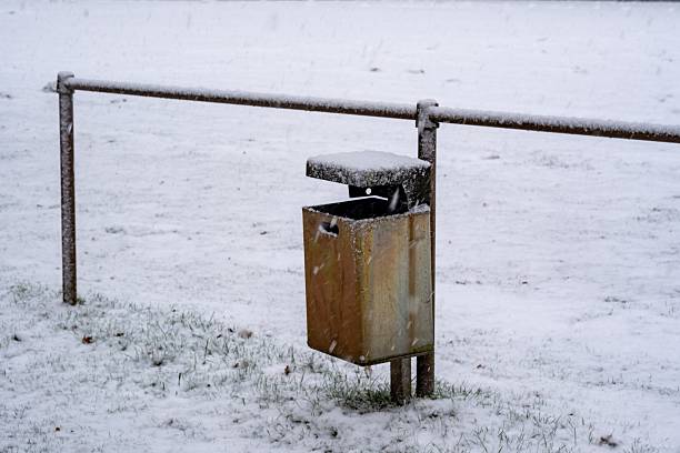 Trash can and railing in a snowy park during winter weather