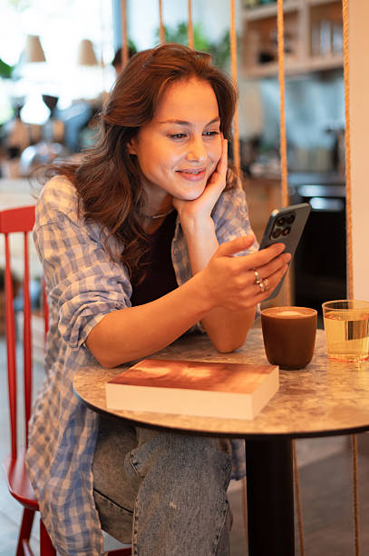 istock Young smiling woman using phone in the coffee shop 2254796254