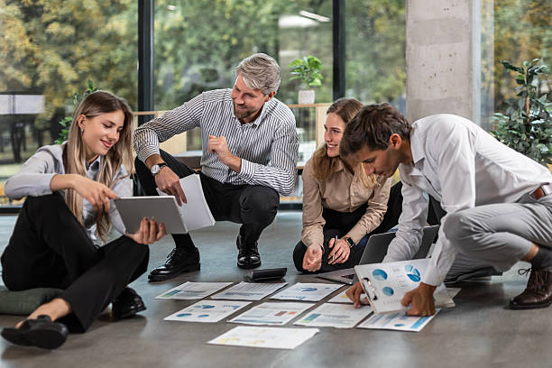 istock Group of young business people working on new project sitting with financial documents spread out on the floor 2254797338