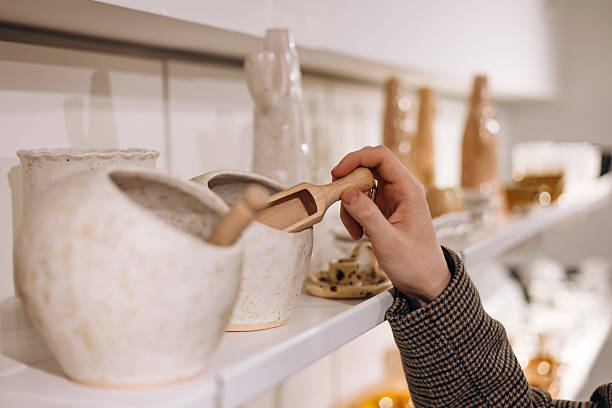 istock Wooden spoon and ceramic storage jar held by hand in clean store display. 2254797408
