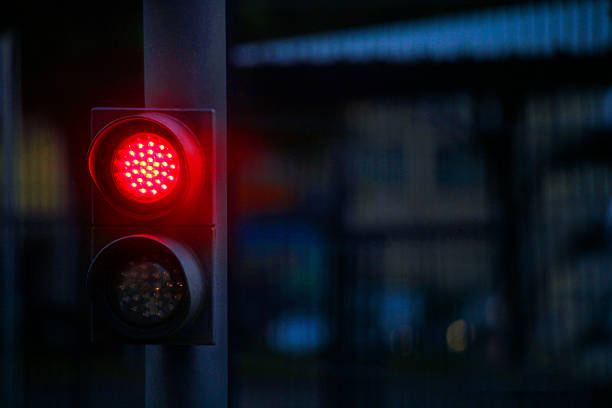 Red light hanging above a paved street in the city,a red traffic light glowing brightly at an urban intersection during the evening rush hour