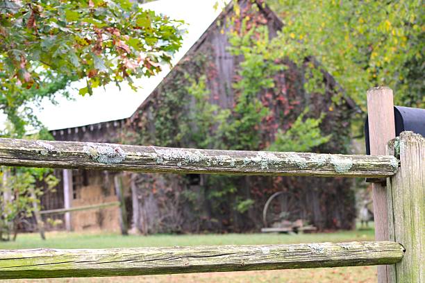 An old farm fence in forefront with a barn in the background and fall colors.