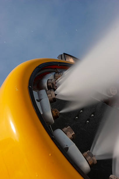 Nuremberg, Germany - 25th May 2025: Close-up of a yellow and grey airplane engine attached to a wing. The engine dominates the frame against a cloudy sky and airport fence.