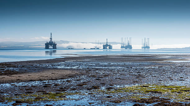 Oil drilling platforms moored in the firth near a low tide beach