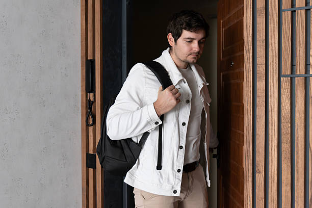 istock Man in white denim jacket with backpack at door 2254804934