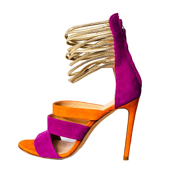 Stylish luxury womens high heel sandals featuring vibrant purple and orange suede design with gold metallic ankle straps photographed in studio isolated on white background for fashion ecommerce and catalogue use