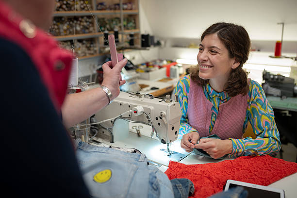 Young seamstress cuts new clothes, repairs old used clothes in a sewing salon, clothing repair shop, sustainable management.